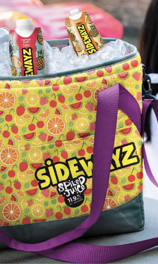 A colorful cooler bag with fruit patterns and a purple strap contains cans and cartons of SIDEWAYZ Spiked Juice on ice. The SIDEWAYZ logo and “Spiked Juice 11.9%” are visible on the bag.